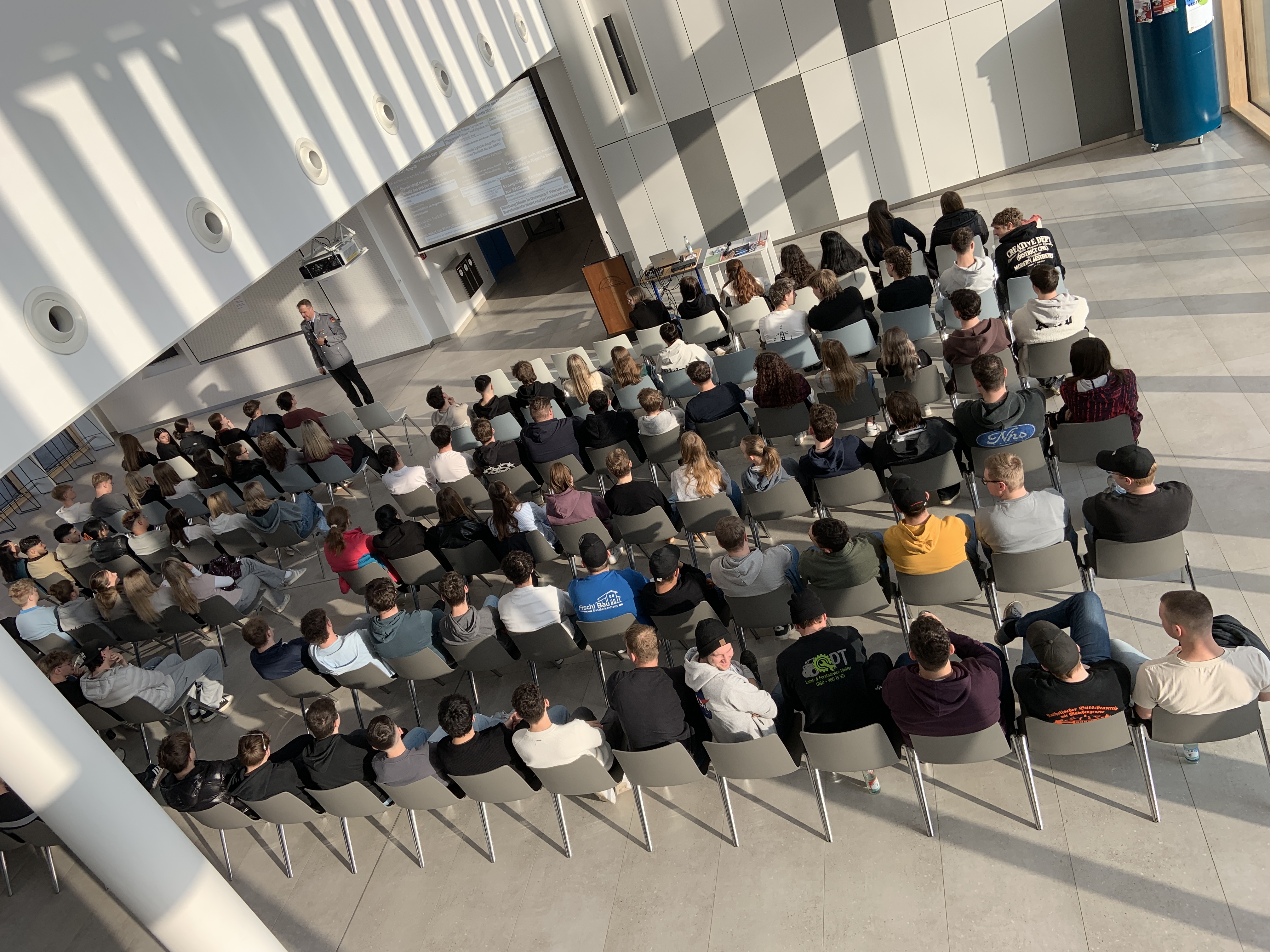 Informationsveranstaltung mit Jugendoffizier Hauptmann Klaus Schedlbauer: Über 100 Schülerinnen und Schüler der kaufmännischen und gewerblichen Berufsschule verfolgen den Vortrag zu aktuellen sicherheitspolitischen Herausforderungen in der Aula der Berufsschule I.